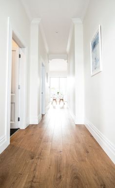 an empty hallway with wooden floors and white walls