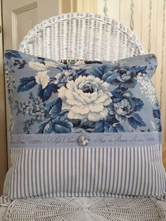 a blue and white pillow sitting on top of a wicker chair