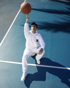 a man in white is holding a basketball on a tennis court with his right hand up