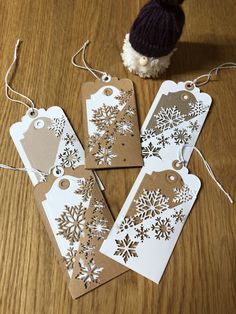 four tags with snowflakes on them are sitting on a table next to a stuffed animal