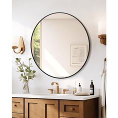 a bathroom vanity with a round mirror above it and wooden cabinets underneath the countertop