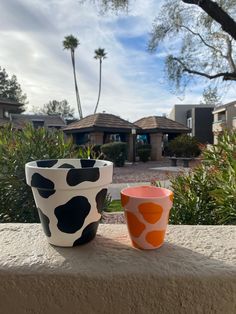 two cups sitting next to each other on a ledge