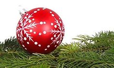 a red ornament sitting on top of a pine tree with white snowflakes