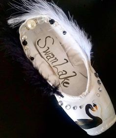 a pair of white shoes with black and white feathers on them that say swanie