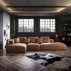 a living room with a large sectional couch in front of two windows and a cowhide rug on the floor