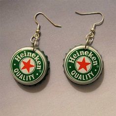 two bottle caps with red and green stars are hanging from silver earwires on a white surface