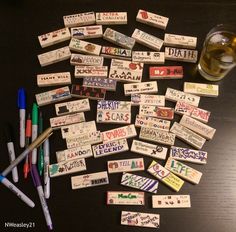 several different types of markers and pens on a table next to a glass of beer