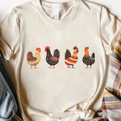 This charming t-shirt features a quirky lineup of beautifully illustrated chickens, each with unique patterns and colors. Perfect for anyone who adores farm life or simply appreciates a fun and whimsical design. The playful and artistic take on these roosters makes this tee a standout piece for casual wear, farm visits, or as a delightful gift for chicken enthusiasts. The lightweight, soft fabric ensures comfort, making it ideal for daily wear. Key Features: Unique and whimsical chicken lineup design Soft and breathable fabric for everyday comfort Perfect gift for farm lovers and chicken enthusiasts Available in various sizes for the perfect fit High-quality print that stands out Machine washable and easy to care for Lineup Design, Rooster Shirt, Rooster Design, Farm Chicken, Whimsical Design, Earthy Colors, Vintage Farmhouse, Farm Life, Style Moderne