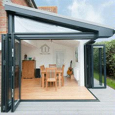 an extension to a house with sliding glass doors on the outside and wooden flooring