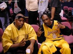 two young men sitting next to each other in front of a crowd at a basketball game