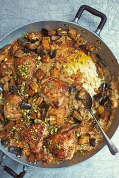 a pan filled with meat and vegetables sitting on top of a table next to a fork