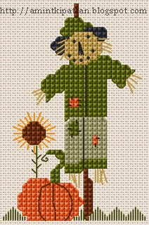 a cross stitch pattern with a cat in a green coat and hat standing next to a pumpkin