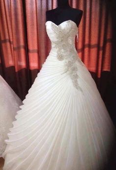 two wedding gowns on display in front of red curtains