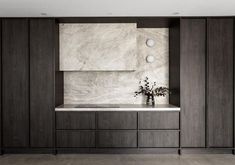 a kitchen with marble counter tops and dark wood cabinetry, along with two vases filled with flowers