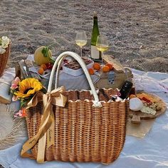 two wicker baskets sitting on top of a blanket next to wine glasses and bottles