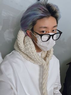 a person with glasses and a scarf around their neck wearing a mask to protect them from the sun