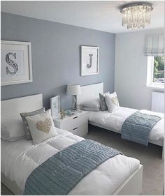 two beds in a room with blue walls and white bedding, one has a chandelier above the headboard