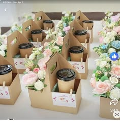 there are many small boxes with flowers in them on the table, and one has a coffee cup