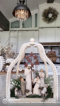 a christmas scene with figurines in the middle of a kitchen counter and lights hanging from the ceiling