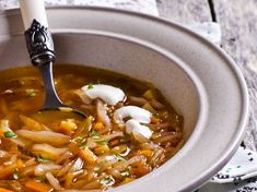 a bowl filled with soup sitting on top of a table next to a white napkin