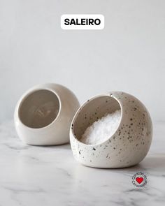 salt and pepper shakers sitting on top of a marble counter next to each other