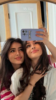 two young women taking a selfie in front of a mirror