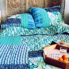 a bed with blue and green bedspread next to a tray of oranges