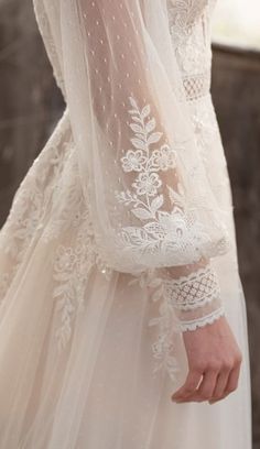 the back of a woman's wedding dress with white lace and pearls on it