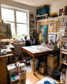 an artist's studio with lots of art work on the walls and desks