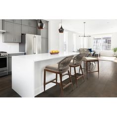 an open kitchen and living room area with bar stools in front of the counter