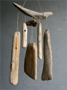 driftwood pieces hanging from strings in front of a gray wall