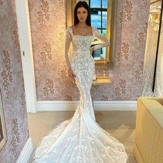 a woman in a white dress standing next to a mirror