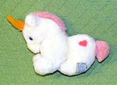 a white stuffed unicorn laying on top of a green cloth covered floor next to a yellow rubber duck