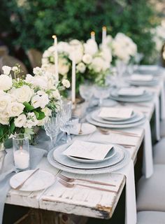 the table is set with white flowers and place settings for an elegant dinner party or special event