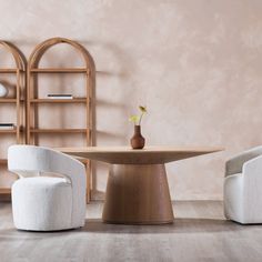 a table with two chairs and a vase on it in a room that has pink walls