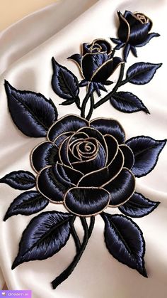 an embroidered rose on the back of a white satin dress with black leaves and swirls