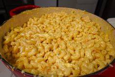 a red pot filled with macaroni and cheese sitting on top of a stove