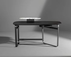 a black table with a white plate on top and some metal legs in the middle