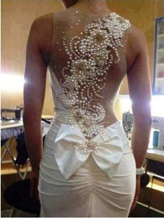 the back of a woman's wedding dress with pearls on it, in front of a computer screen