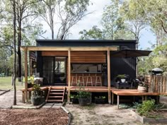 two people sitting on wooden benches in front of a tiny house