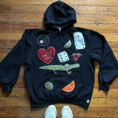 a black hoodie with dice, hearts, and alligator on it next to white shoes