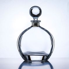 an empty glass bottle with a silver stopper on top is sitting on a reflective surface