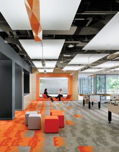 an office with orange and gray carpeting, two people sitting at desks