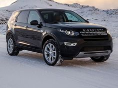 a black land rover is driving through the snow