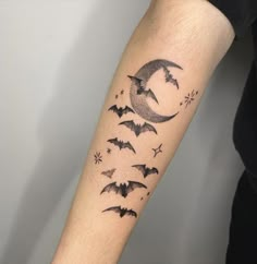 a person with a tattoo on their arm that has bats flying around the moon and stars