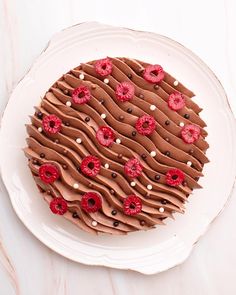 a chocolate cake with raspberries on top and frosting in the shape of a circle