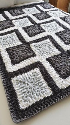 a black and white crocheted blanket sitting on top of a bed