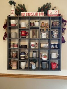 a shelf filled with cups and mugs on top of a wall next to a christmas tree