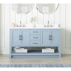 a bathroom vanity with two mirrors above it and towels on the floor next to it