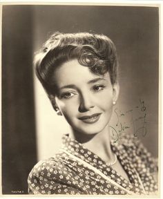 an old black and white photo of a woman with short hair wearing a floral shirt